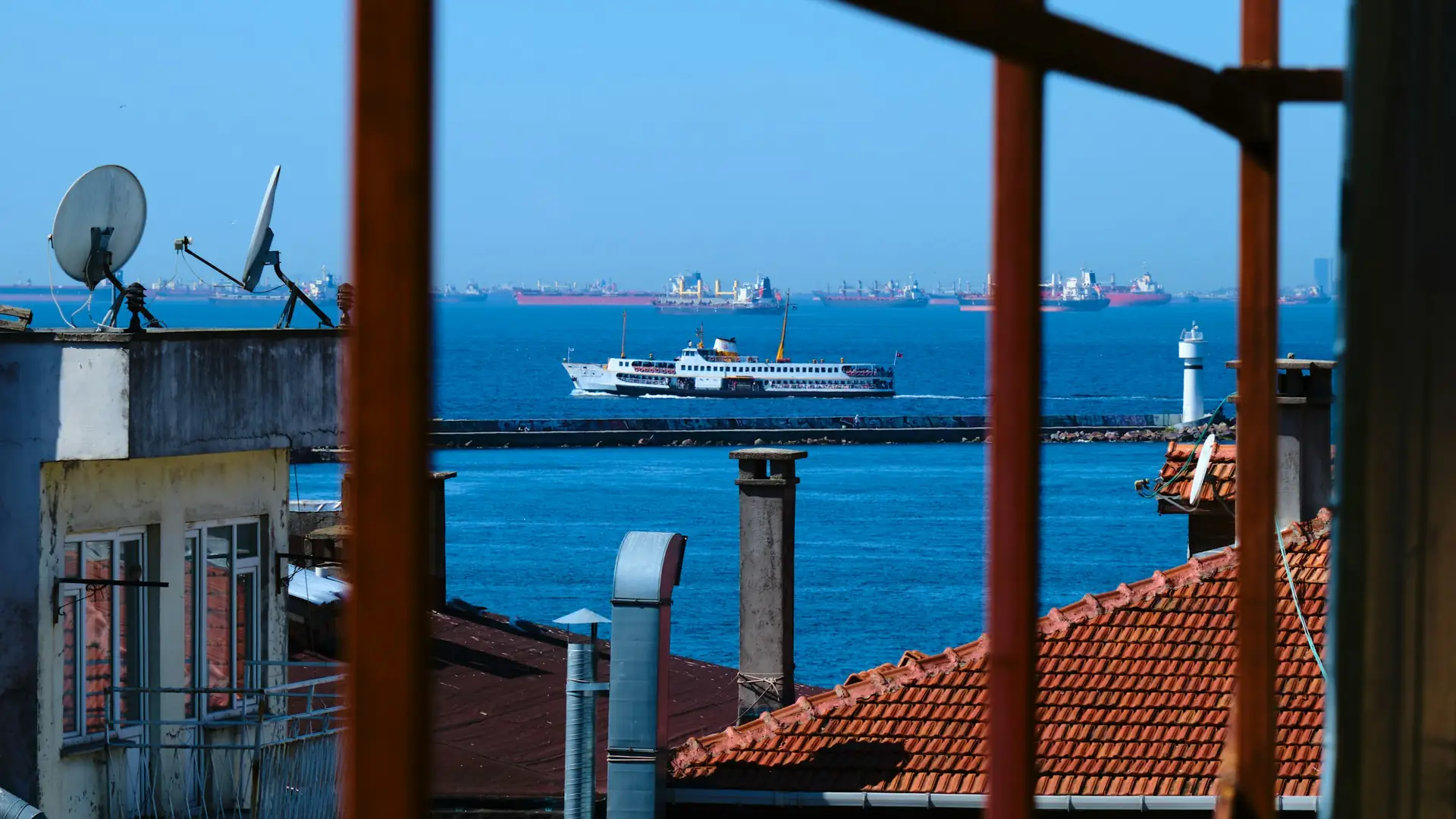 Kırmızı kiremitli çatıların ardında İstanbul Boğazı'ndan geçen vapur
